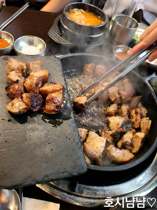 상암일미락 직원이 불판 위에 고기 올리는 장면