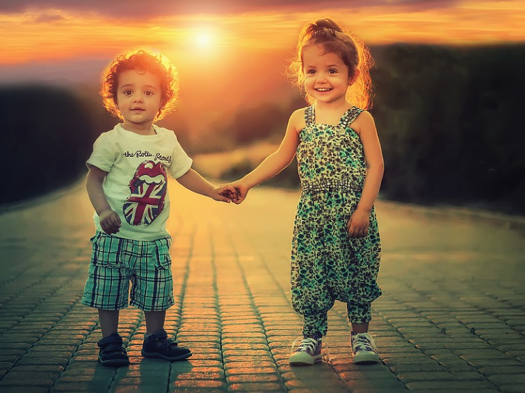 석양이 지는 저녁 노을에 어린 남매가 손을 잡고 있는 사진