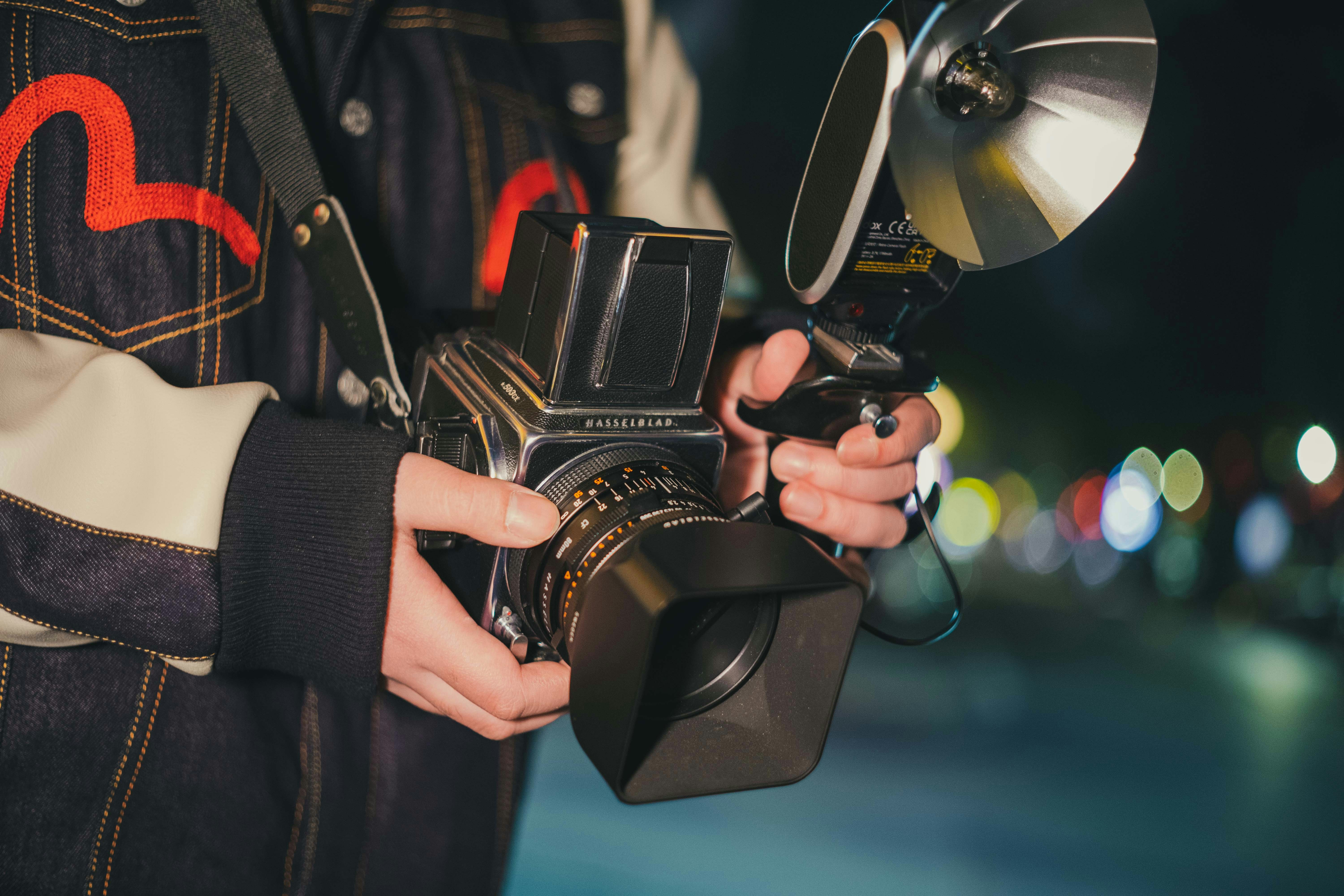 밤에 길거리에서 누군가가 핫셀블라드와 휴대용 조명을 들고있는 사진