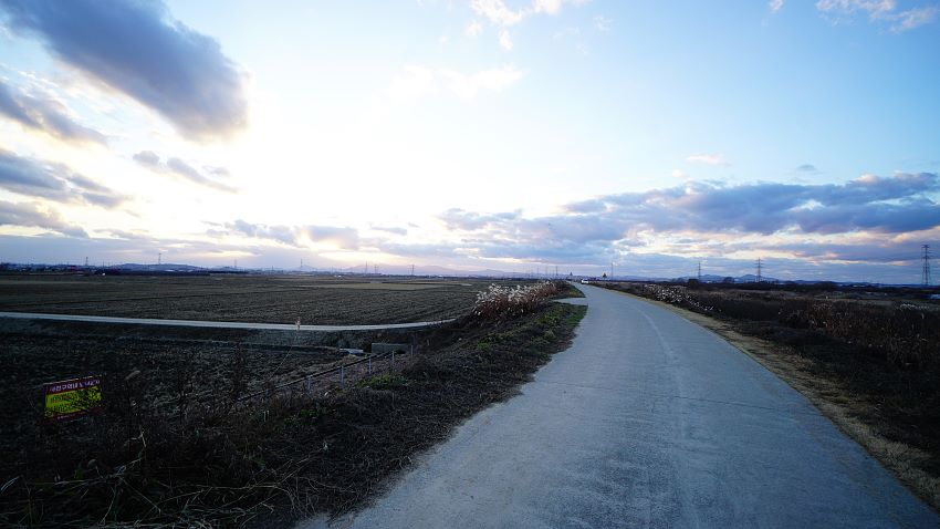 왼쪽으로 완만하게 굽어지는 득방길, 좌 우에 드넓은 들판, 푸른 하늘에 회색구름,