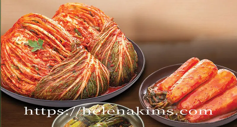 세라믹 접시에 배추김치, 총각김치, 갓김치가 담겨 탁자 위에 놓여 있는 이미지.