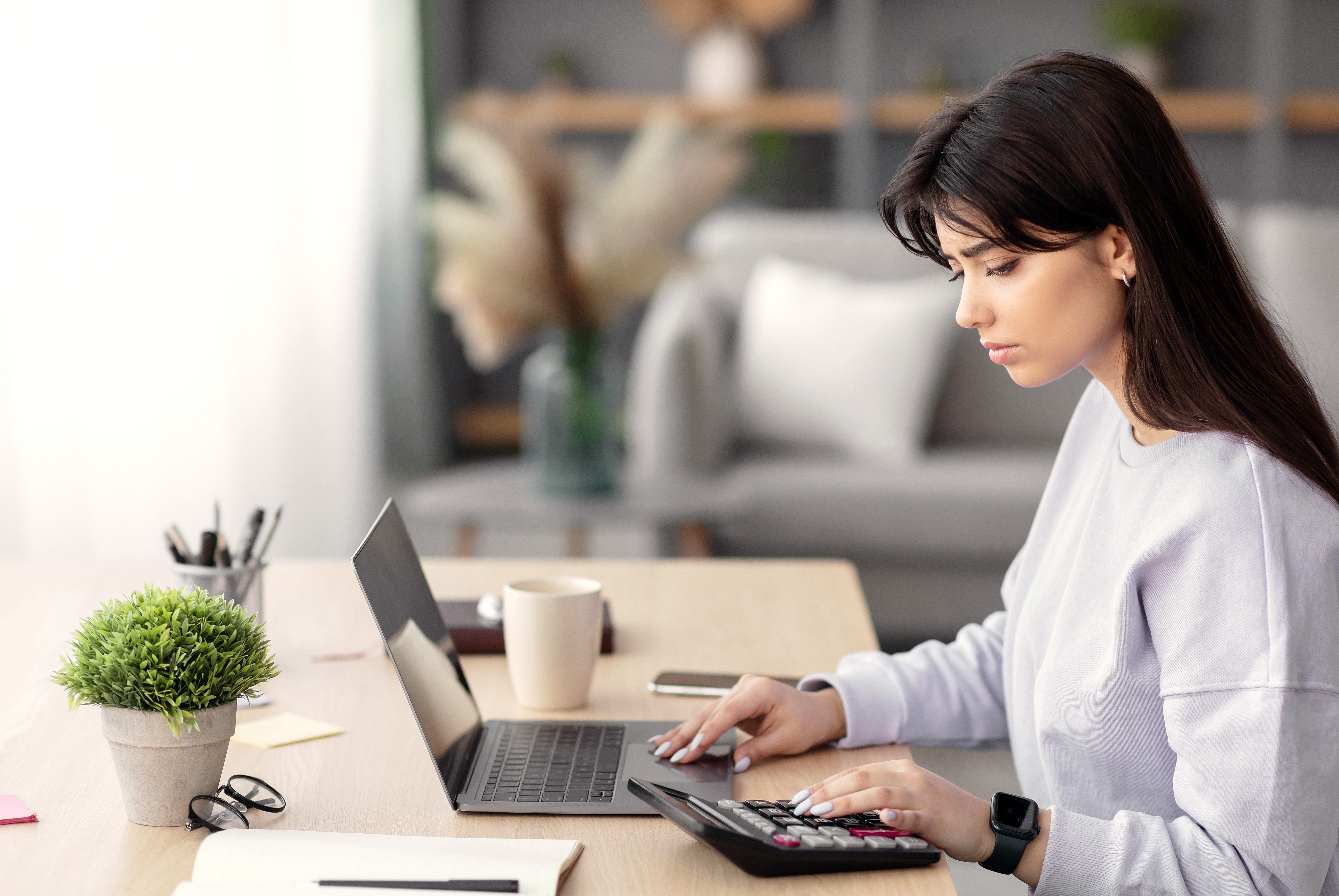 노트북과 계산기를 사용하며 재무 계획을 세우는 여성｜2025년 청년도약계좌 정부 기여금 확대와 부분 인출 가능 혜택 안내