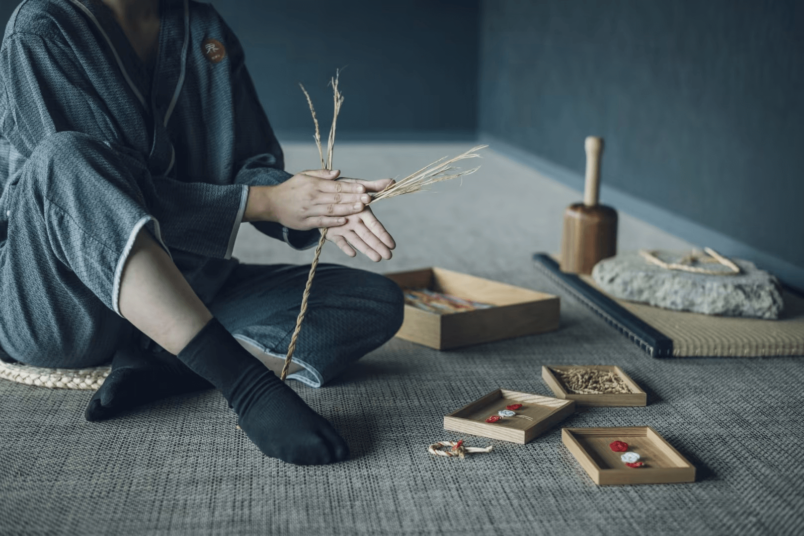 짚 매듭을 제작 중인 체험 참가자의 모습, 전통적인 도구와 짚 재료가 함께 배치된 공간