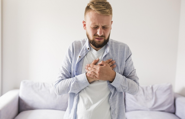 가슴 통증을 호소하며 손으로 가슴을 누르고 있는 남성의 모습