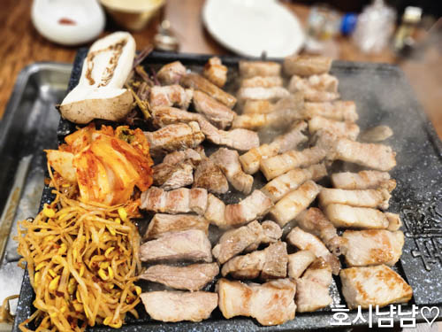 제주덕구 불판 위에서 익어가는 제주 돼지고기와 김치, 콩나물, 고사리