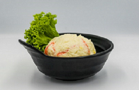 검은 그릇에 감자를 으깨어 만든 감자 샐러드가 동그란 반구 모양으로 담겨 있고 한쪽에 상추로 장식되어 있다