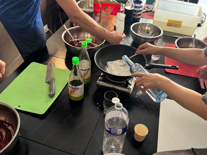 Participants mixing red pepper paste in stainless steel bowls at Midam Paris cooking class, atelier cuisine coréenne