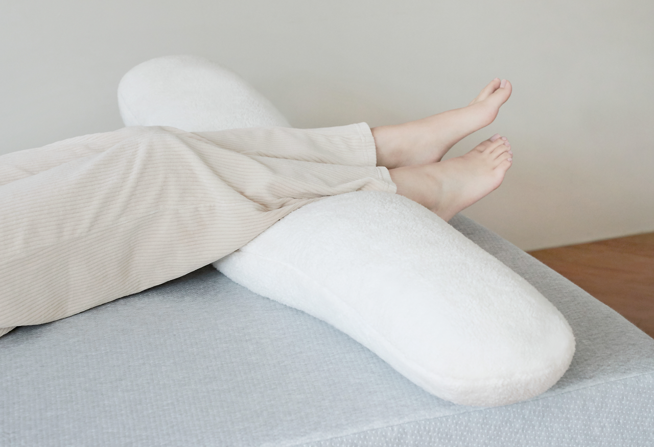 정면으로 누워 무릎 밑에 베개를 둔 사진