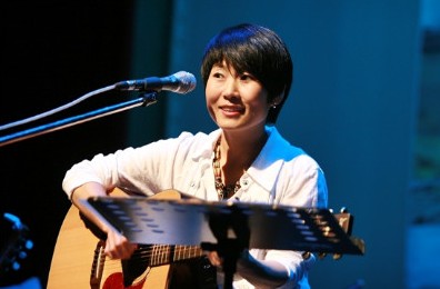 박강수-꽃이-바람에게-전하는-말-숏컷을-한-박강수가-무대위에-앉아-옅은-미소를-띄고-있는-사진