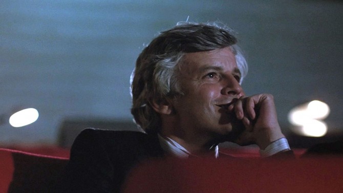 시네마 천국에서 남자가 극장 안에서 미소를 지으며 영화를 감상하는 장면