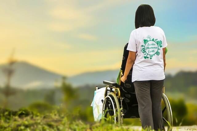 휠체어 탄 노인과 함께하는 젊은 여성