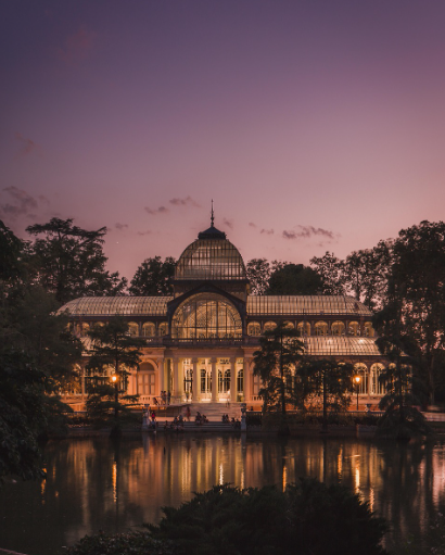 마드리드의 크리스털 팰리스, 앞에 연못이 있고 저녁이라 건물 안에 불이 켜져 있어 몽환적인 분위기를 보여준다.