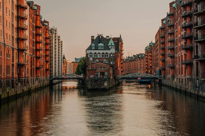 함부르크 슈파이허슈타트 중심에 위치한 바서슐로스, 붉은 벽돌 건물 사이 운하 위에 세워진 독특한 구조의 건물과 노을빛 풍경