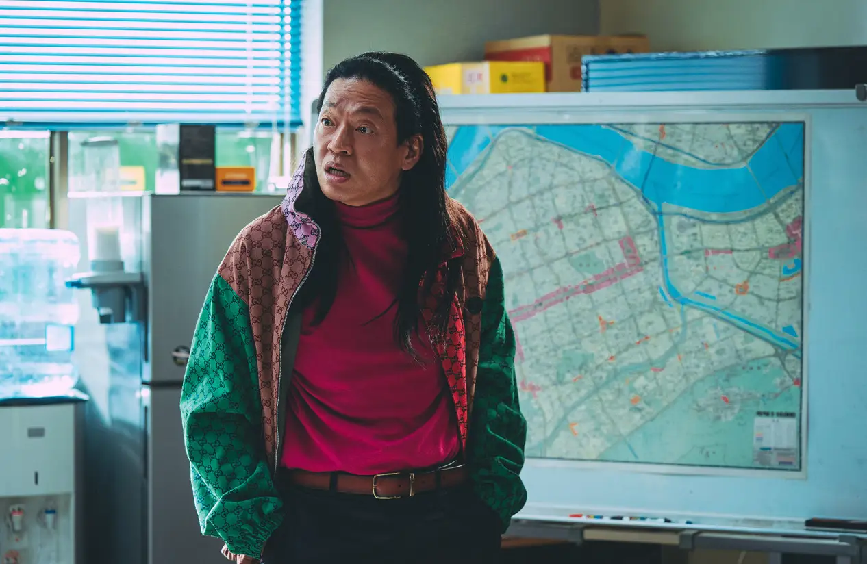 범죄도시-알록달록한 옷을 입고 주머니에 두손을 꽂은채 지도앞에 서서 누군가에게 따지는 장이수