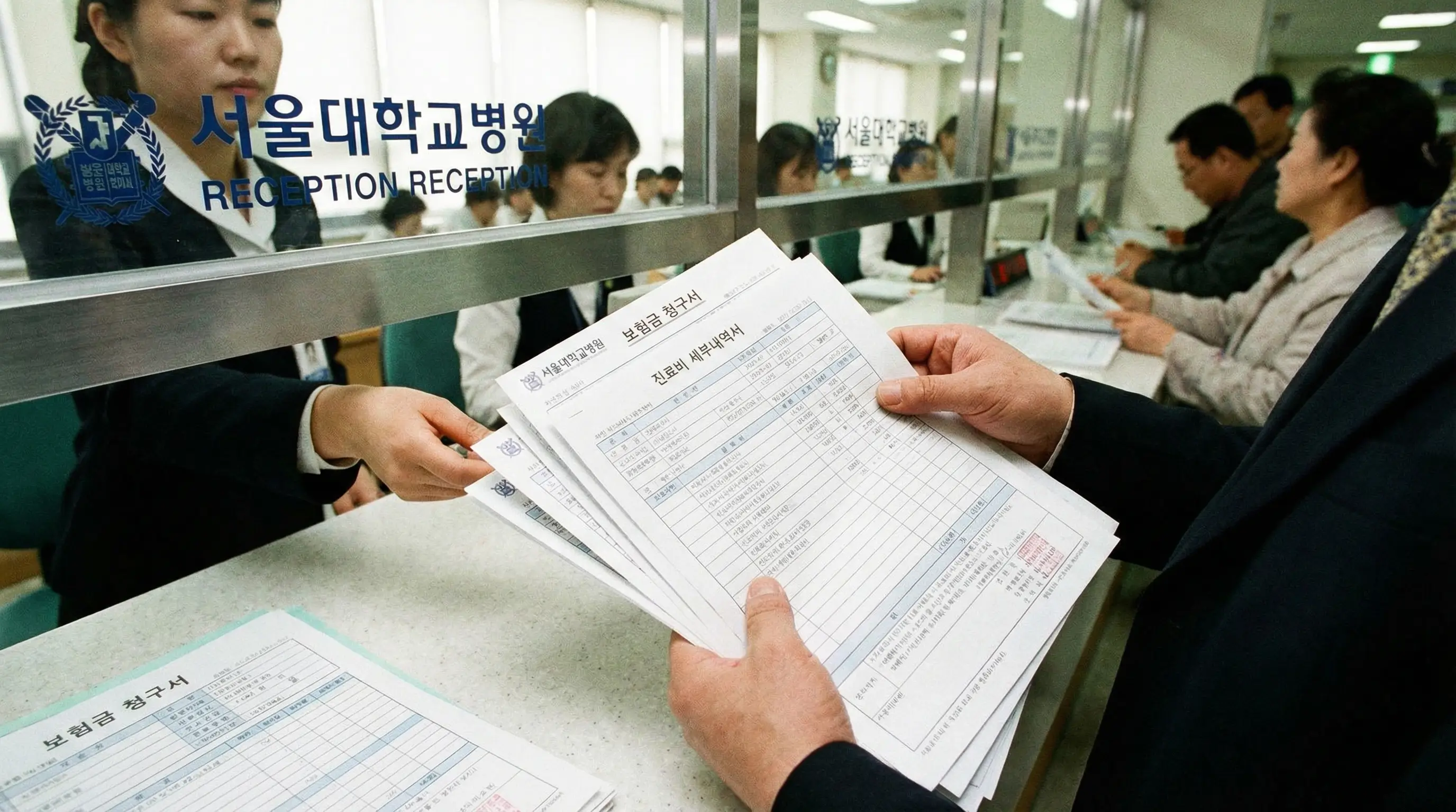 병원 원무과 창구에서 진료비 세부내역서를 발급받으며 보험금 청구 서류를 챙기는 환자의 손