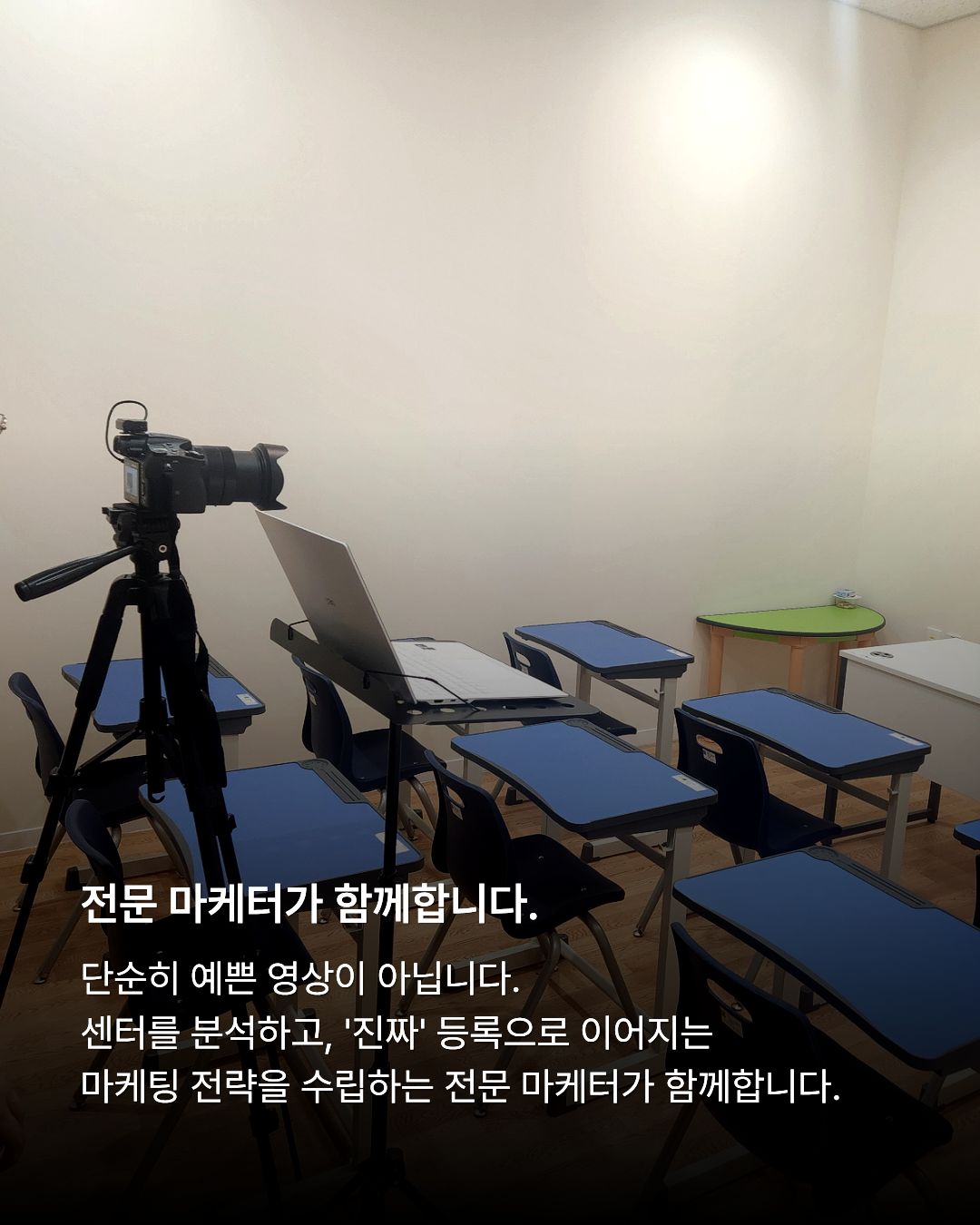 파란색 상판의 아동용 책상과 의자들이 정돈된 센터 내 교실 공간에 삼각대에 고정된 DSLR 카메라와 노트북이 촬영을 위해 세팅되어 있는 전경. 하단에는 진짜 등록으로 이어지는 전략을 수립한다는 마케터 관련 문구가 적혀 있습니다.
