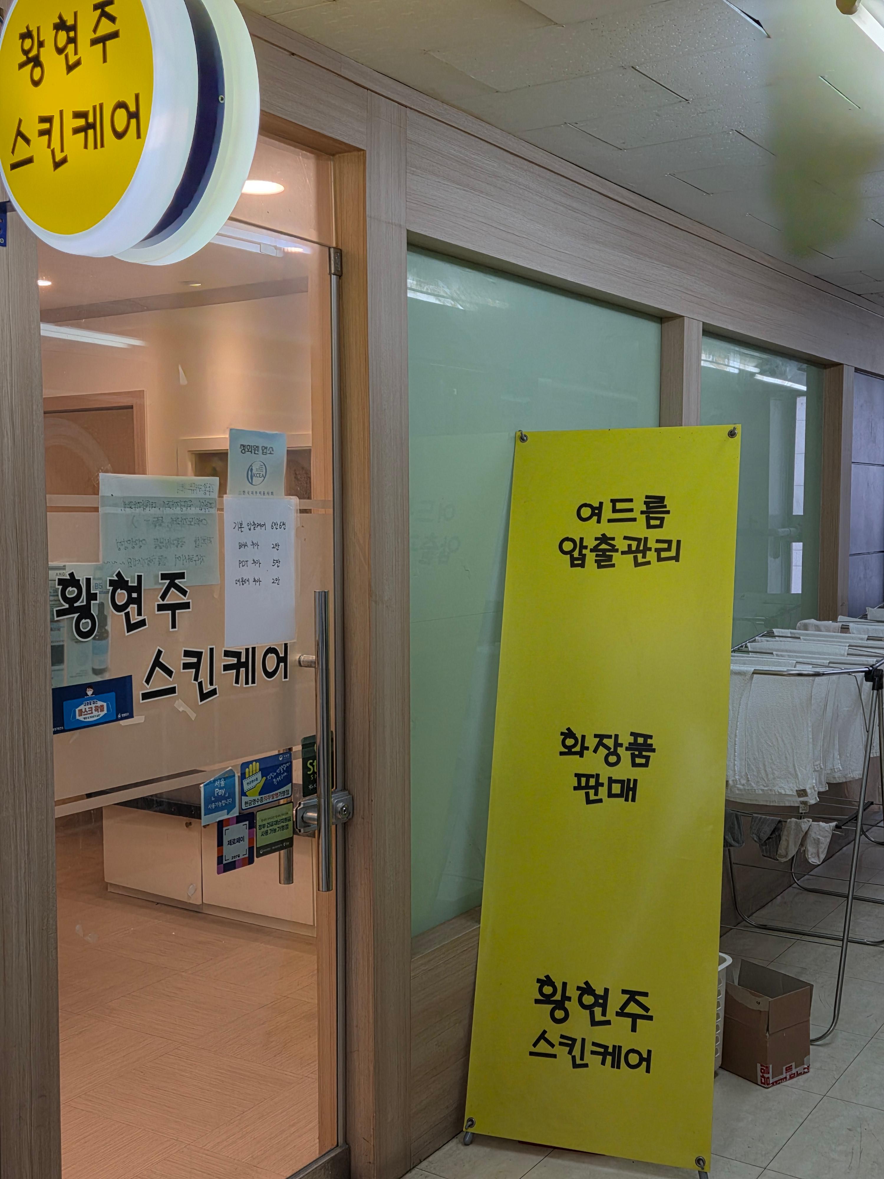 황현주 스킨케어 매장 입구 간판과 여드름 압출 관리 안내 현수막