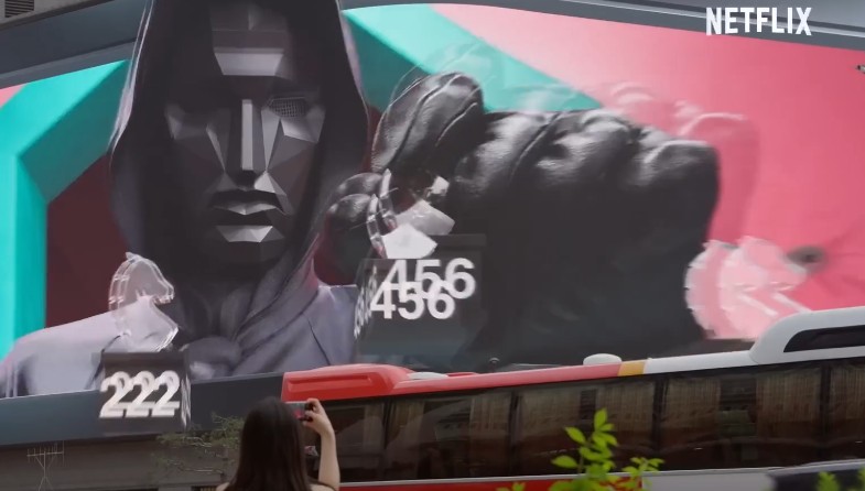 오징어 게임 홍보를 위한 대형 디지털 광고판, 참가자 번호와 가면 캐릭터가 강조된 화면