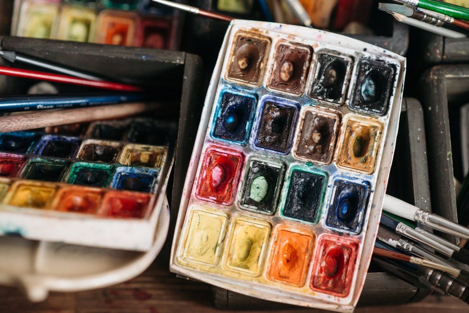 Close-up of a colorful watercolor paint set with various brushes, perfect for art projects.