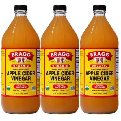 투명한 병에 검음색뚜껑을 가진 유리병 3병이 있다. 노랙색 바탕의 빨간색과 하얀색으로 글씨가 써진 브래그 로우 언필터드 사과 식초 946ml 3병이다.