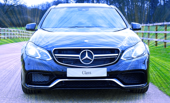 파란 색의 멋진 자동차가 도로에 주차된 정면 모습으로 햇살을 받아 빛이 난다.