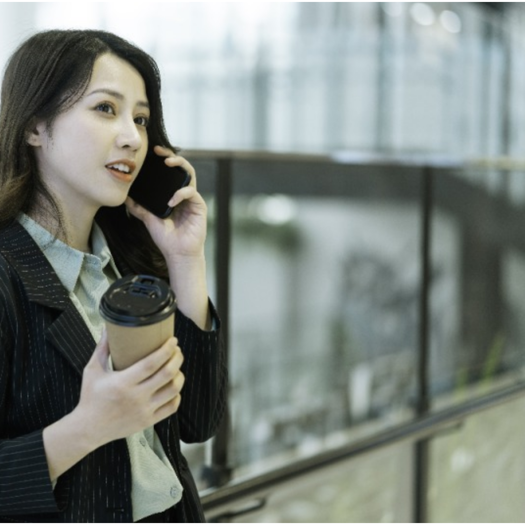 한 여성이 커피를 들고 전화 통화를 하고 있다.