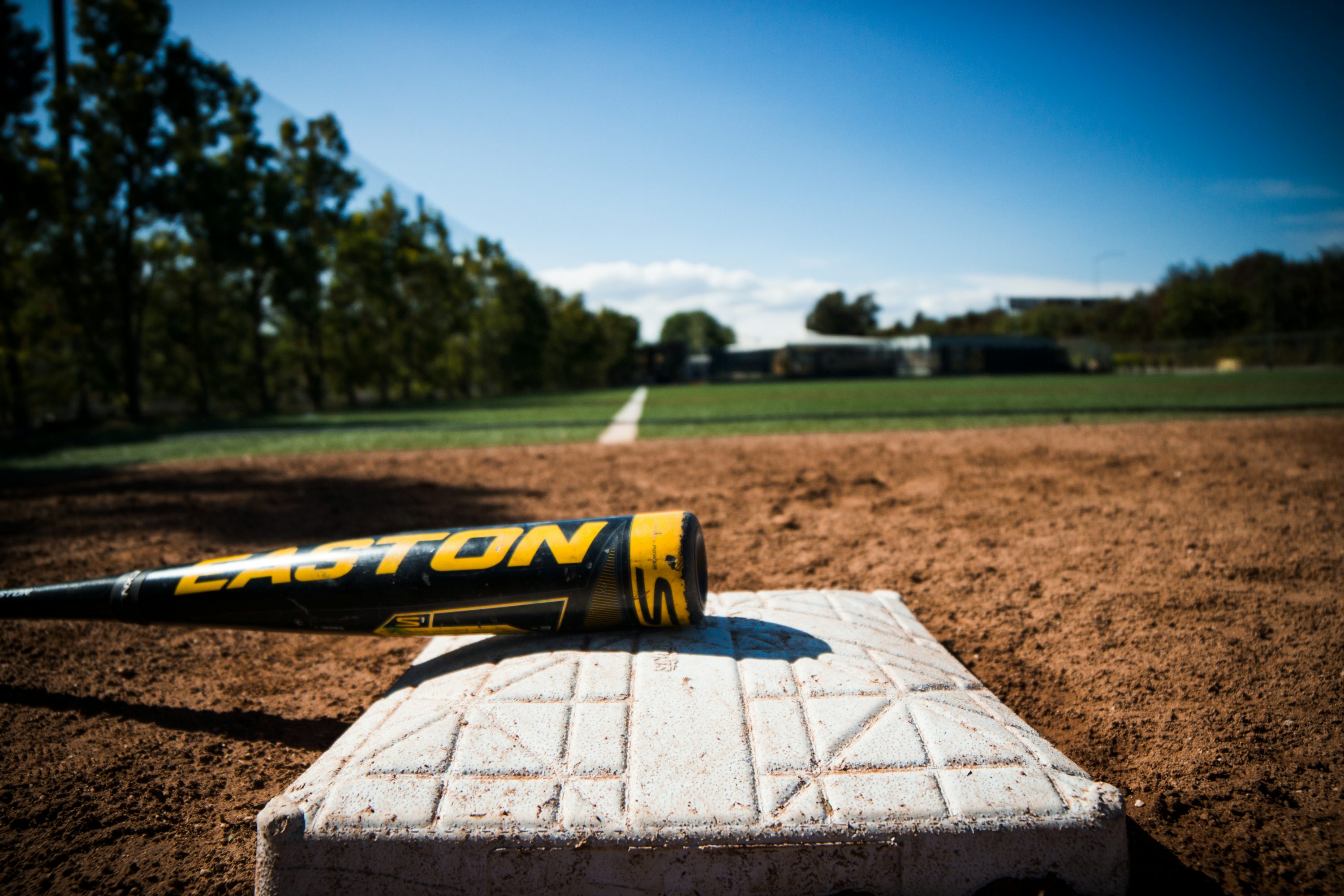 야구장 베이스 위에 검정색 야구배트가 놓여져 있다.&amp;#44;