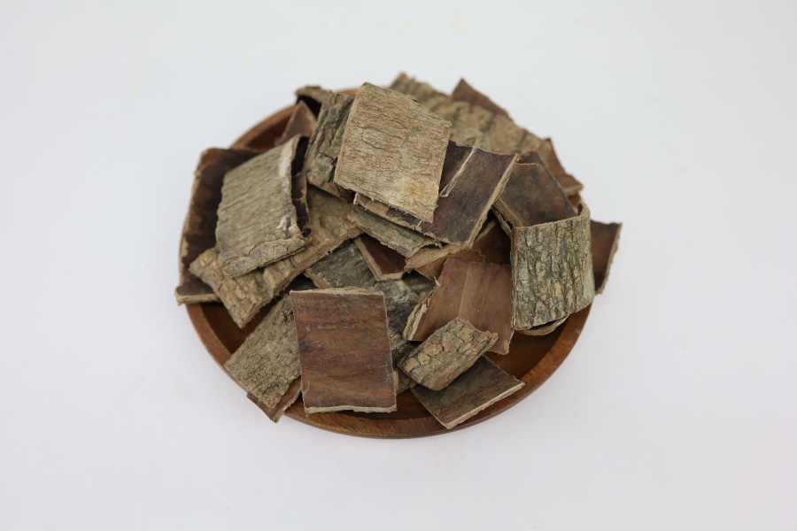야생에서 채취를 한 두충나무의 껍질을 잘 세척한 후에 건조하여 크게 자른 두충을 고동색의 동그란 그릇에 수북하게 쌓아두고 찍은 사진