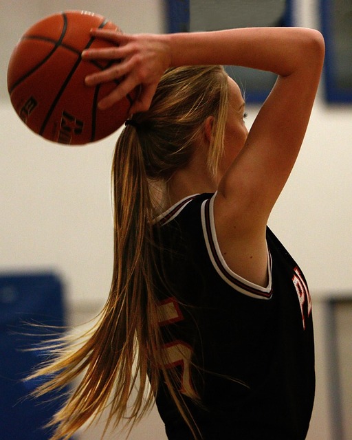 Female basketball player driving to hoop in competitive indoor game with intense focus and athleticism