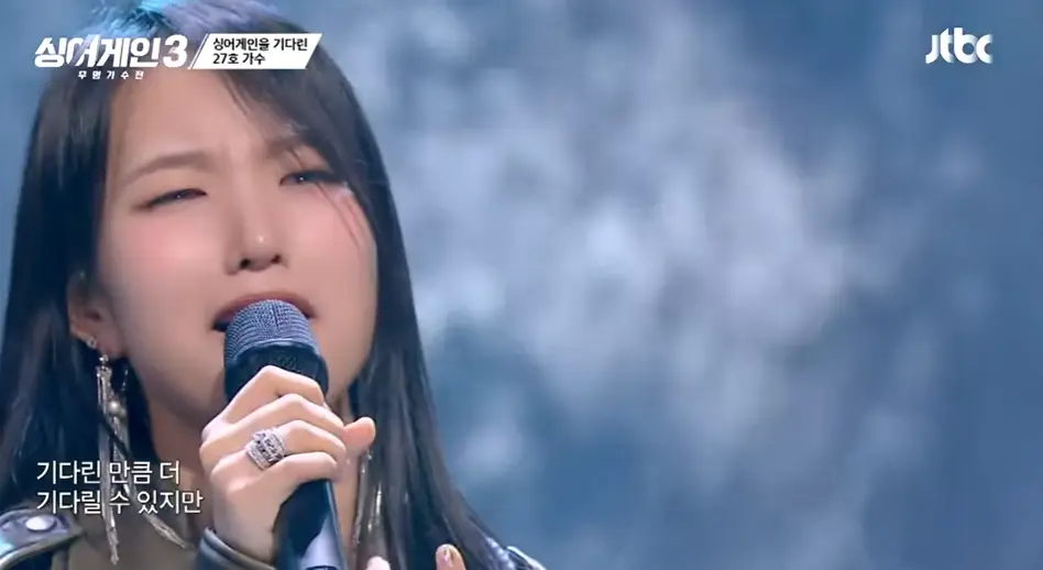 싱어게인3- 긴생머리에 오른손으로 마이크를 쥐고 슬프게 노래하는 27호