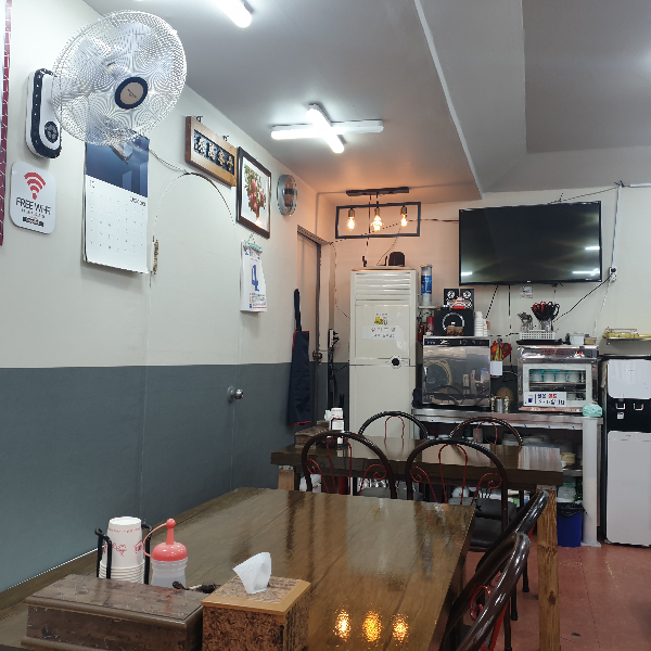 전형적인 중국집 테이블. 벽에는 선풍기가 달려있다 뒤쪽에는 에어컨과 TV가 있다.