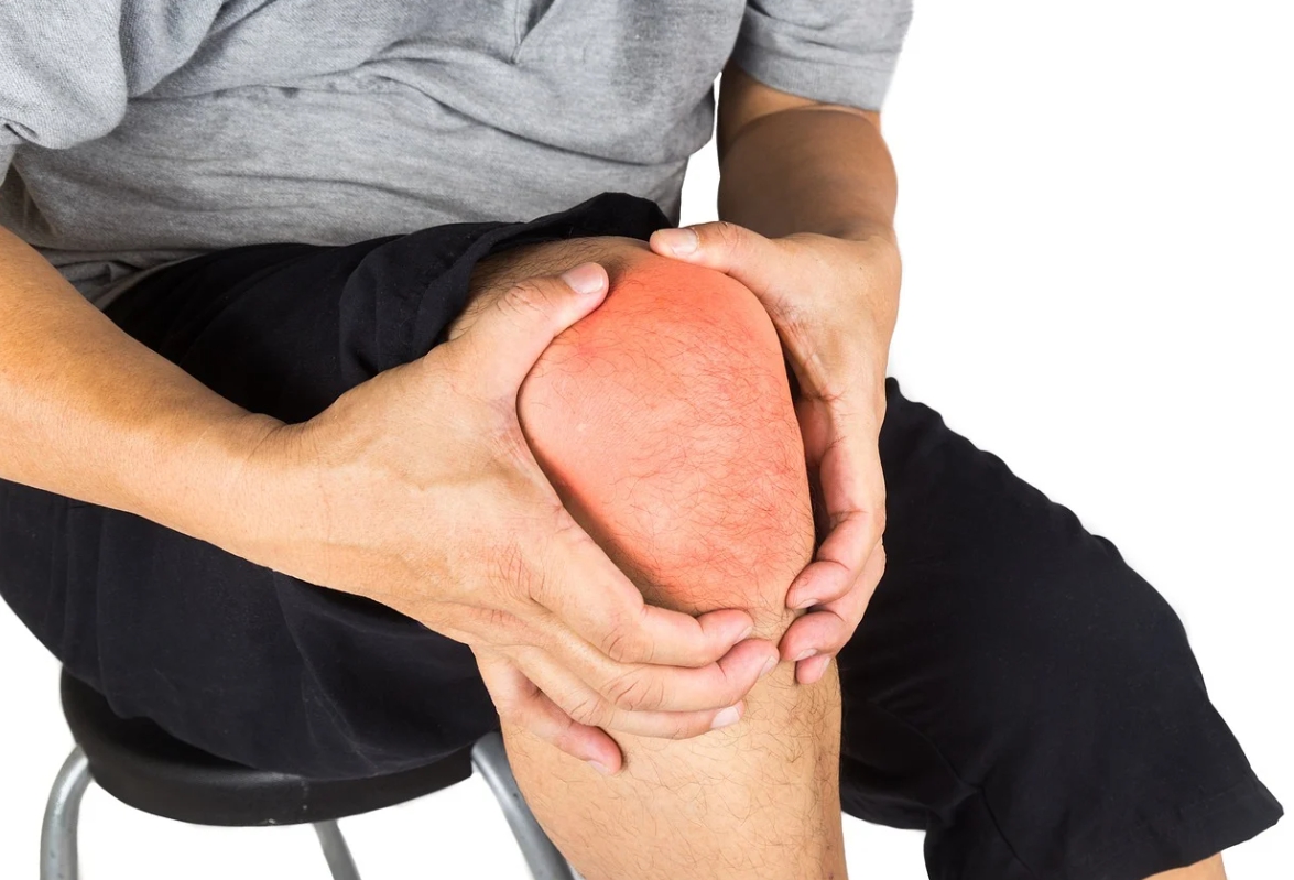 남성이 무릎 통증으로 앉아서 양손으로 무릎을 잡고 있는 사진