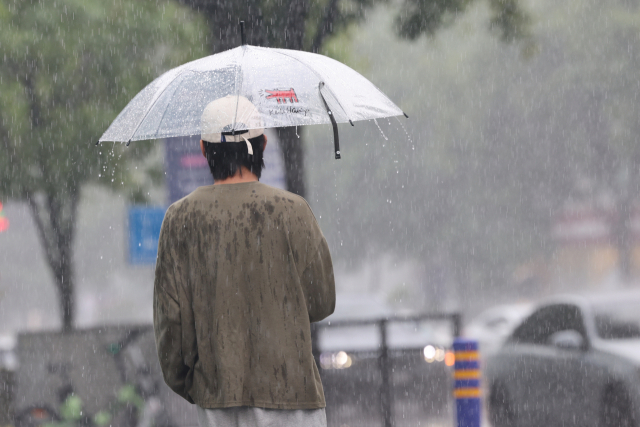 남성이 비가내려 우산을 쓰고 있습니다.