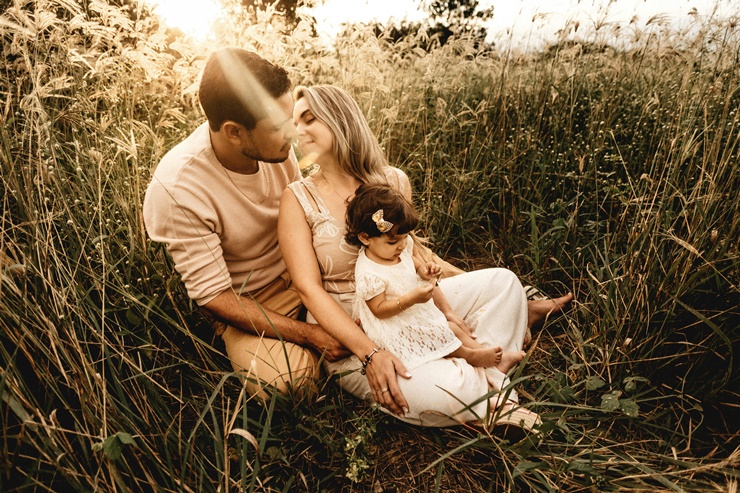 풀밭에 앉아 있는 부모와 아이의 다정한 모습