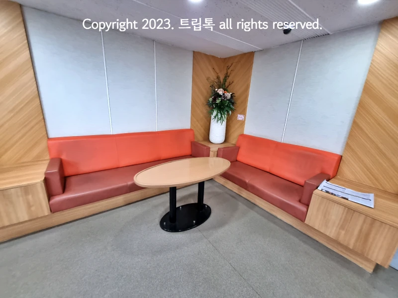 붉은 의자롸 주황 등받이가 있고 가운에 둥근 테이블이 있는 휴게공간
