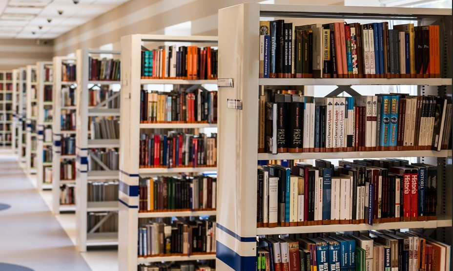 줄지어 차례로 늘어서 있는 책장에 수많은 책들이 꽂혀 있는 사진