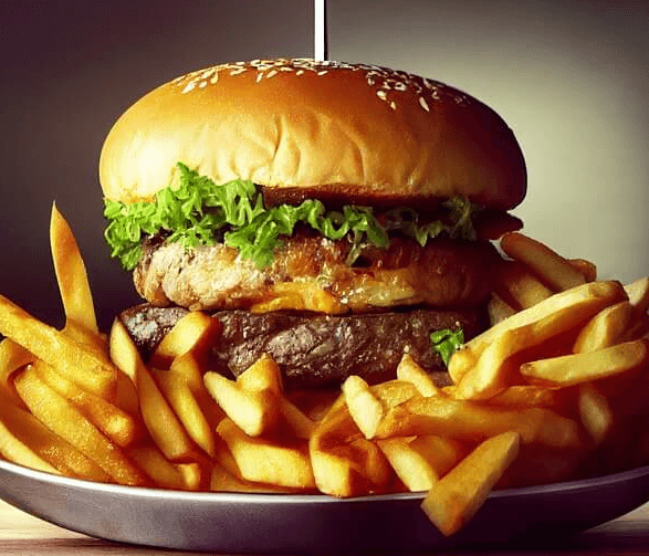 접시 위에 소고기 패티가 아주 두툼한 햄버거와 감자튀김이 한가득 담겨있다.