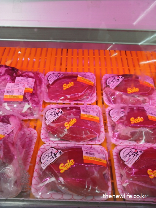할인 스티커가 붙은 포장된 돼지고기가 냉장 진열대에 놓여 있는 모습
