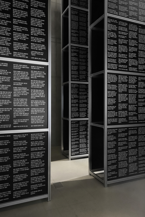 국립대체미술관 설치물. 사람의 키를 넘어서는 높은 크기의 설치물이다. 설치물에는 검은 바탕에 하얀 글씨가 빼곡히 적혀있다. 