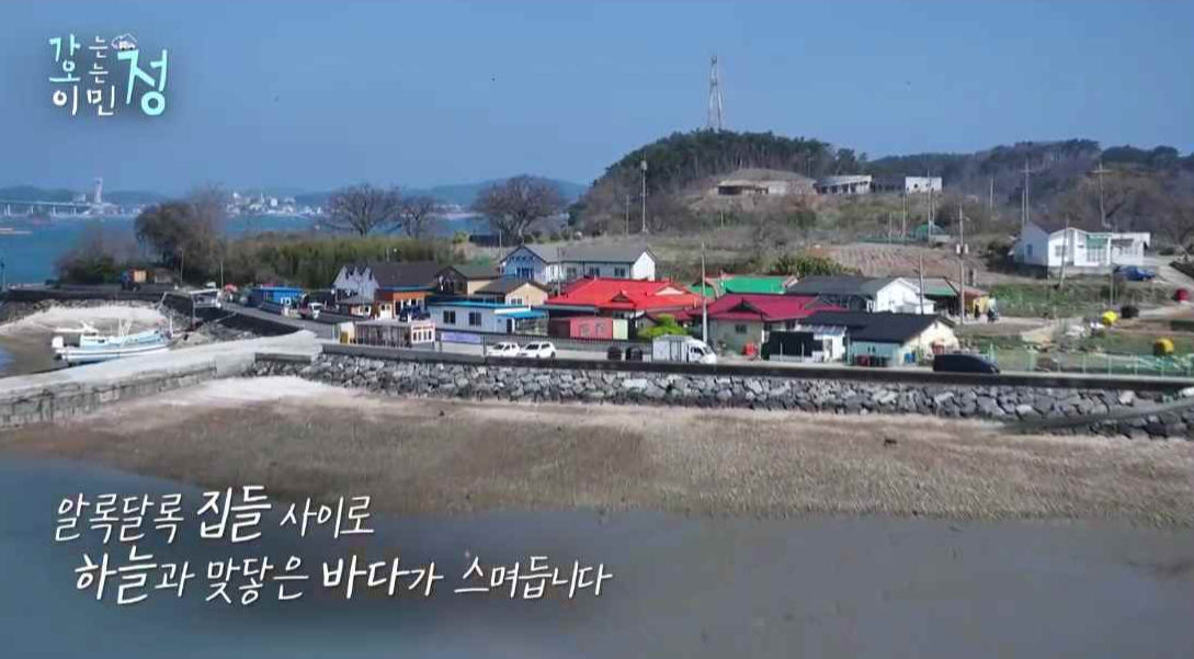 효자도 해변과 집들을 바다 쪽에서 보는 장면에 알달다록 집들 사이로 하늘과 맞닿은 바다가 스며듭니다 자막이 있는 스틸컷