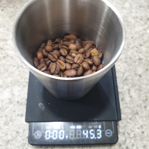 대리석 위에 원두가 담긴 컵이 있다. 저울은 45.3g을 나타내고 있다.