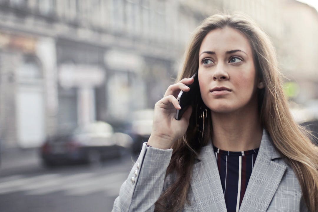 도심 속 통화 중인 여성, 금융기관 사칭 전화를 받는 긴장된 표정