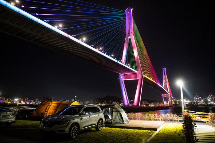 불켜진 부산항 대교 밑에 있는 캠핑장전경과 텐트 모습