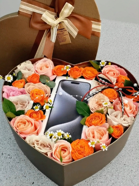 하트모양의상자에꽃과최신휴대폰을담아선물을준비한사진