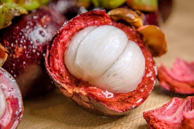 망고스틴이 반으로 잘라져 알맹이가 보이는 사진입니다.