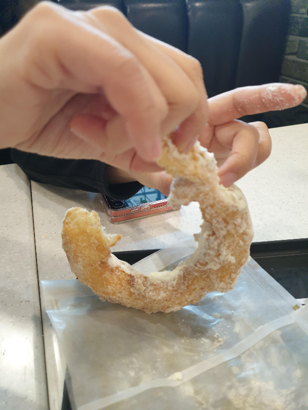 밀크 도넛을 손으로 뜯는 모습. 손가락에 밀크 파우더가 묻어있다.