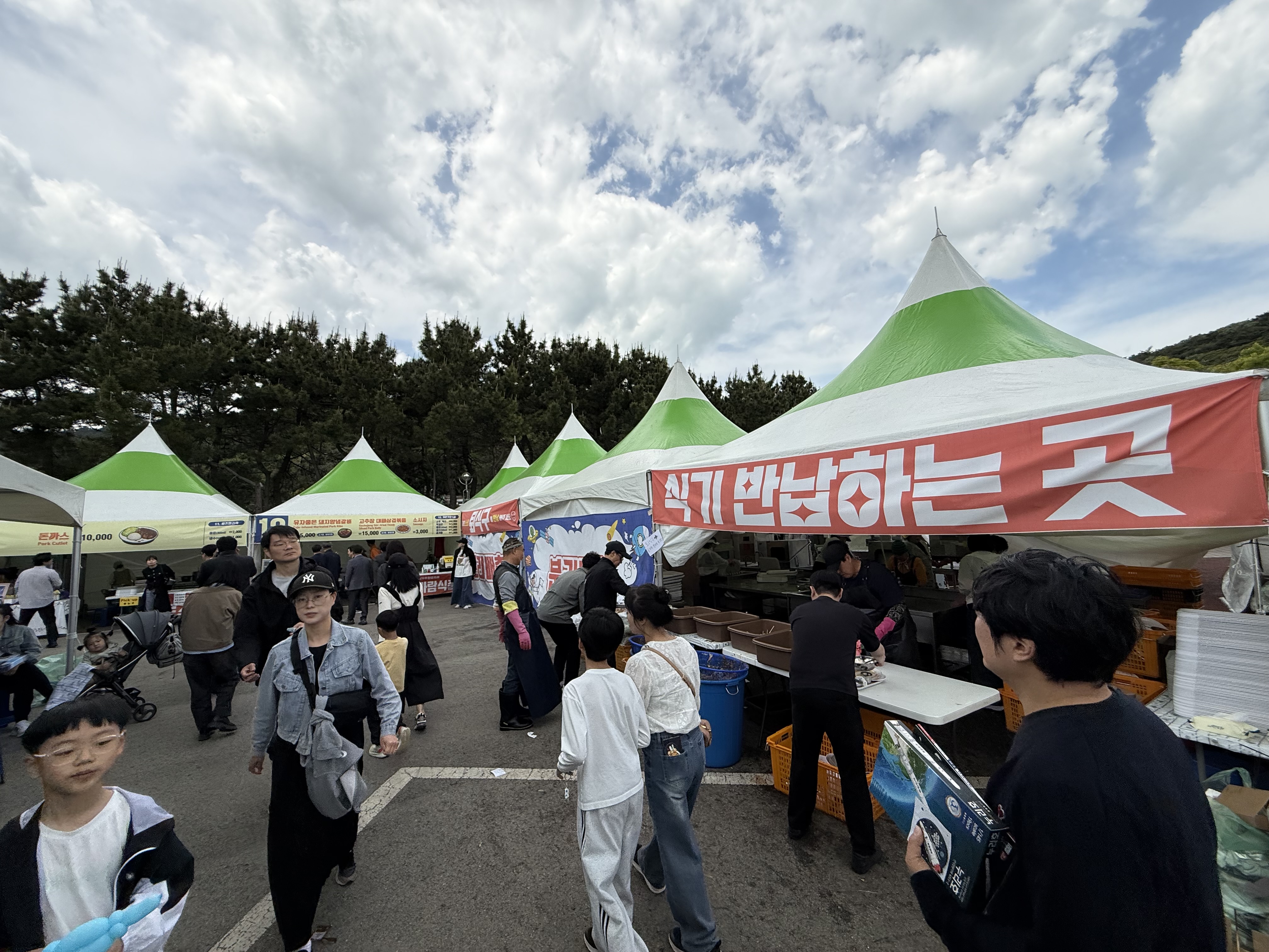 고흥우주항공축제장의 식기 반납 및 음식 준비 구역입니다. 하얀색과 초록색 천막 아래 직원들이 분주하게 일하고 있으며, 빨간색 현수막에 '식기 반납하는 곳'이라는 문구가 보입니다.