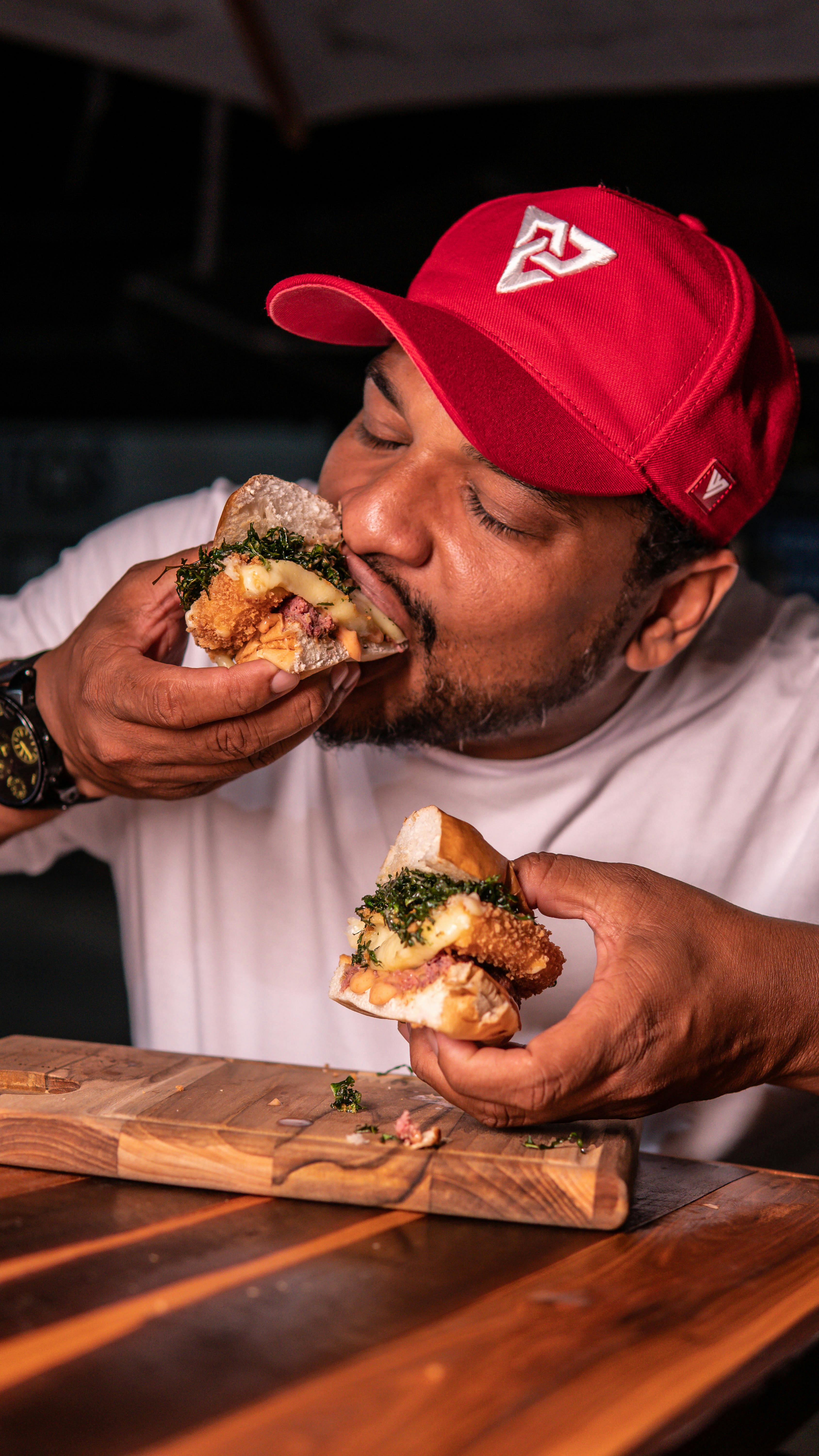 햄버거를 반쪽으로 쪼개어 양손으로 들고 한입 베어먹는 장면