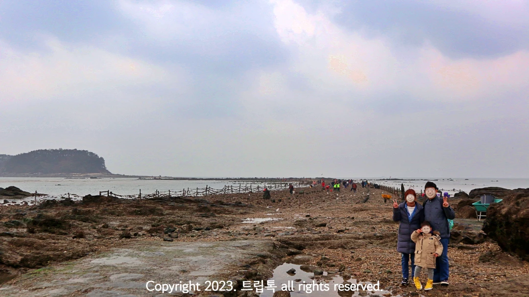 무창포 신비의 바닷길을 배경으로 세사람이 사진을 찍는다