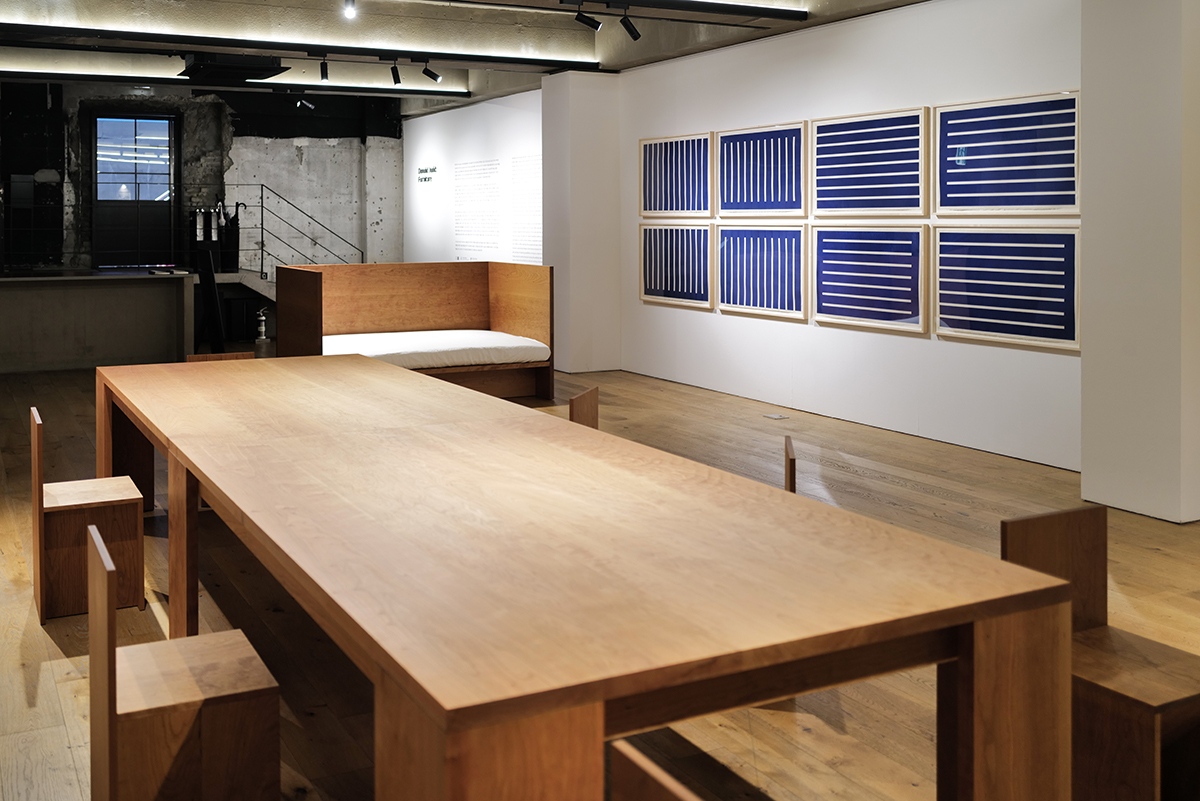 한 전시에서 멀리 벗어나 전체를 찍은 사진. 책상과 의자 그리고 액자가 보이지만 특유의 왜곡으로 인한 공간감이 사진에서 보인다.